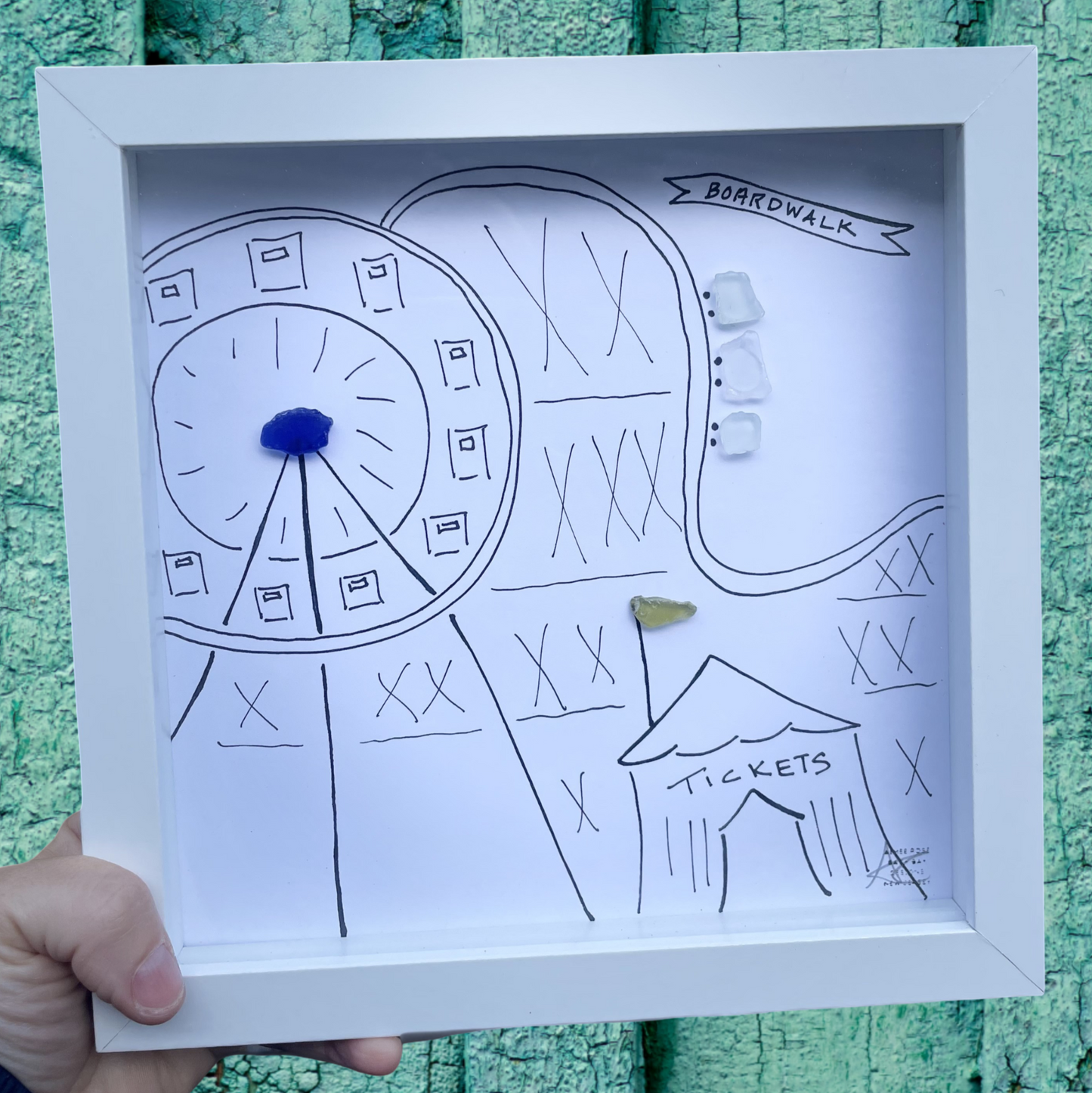 Hand-drawn map of a boardwalk scene in a white frame boardwalk sea glass art