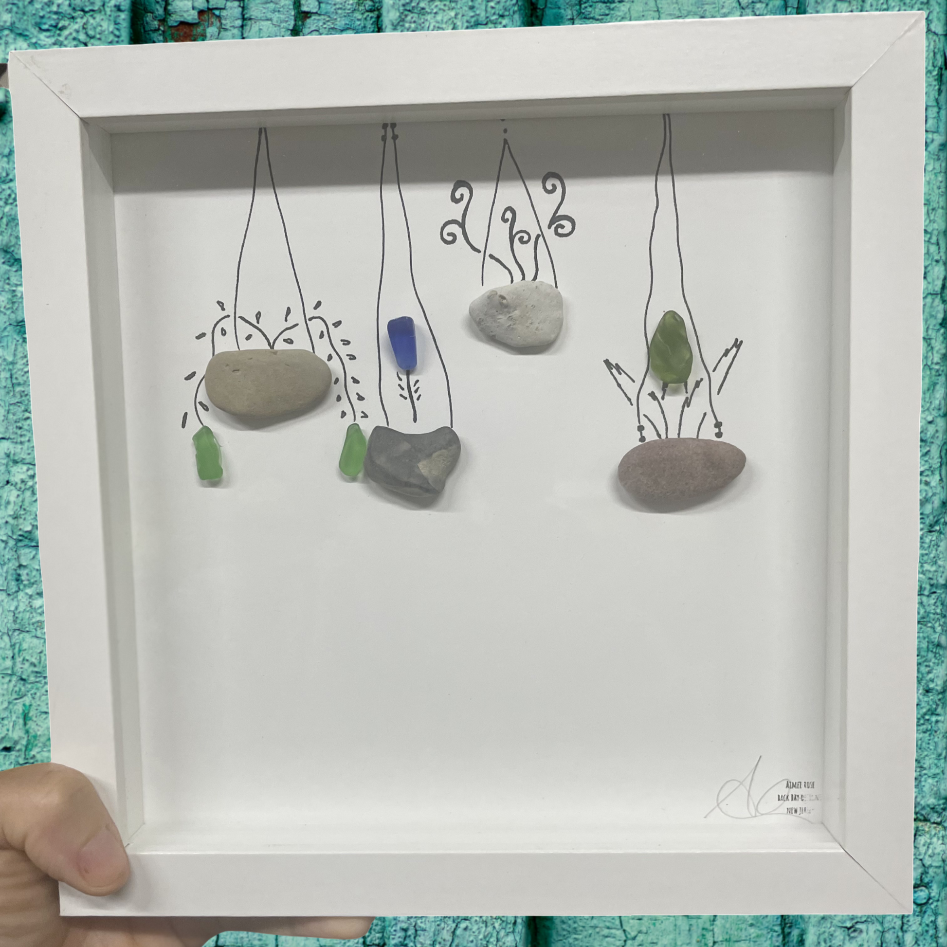 Decorative wall art with pebbles and sea glass plants in a white frame sea glass art