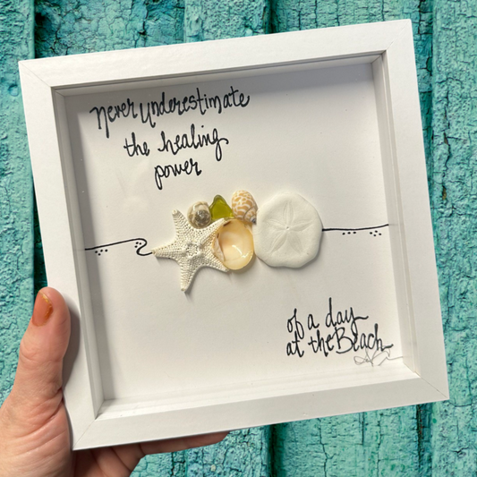Framed artwork with beach-themed elements and text never underestimate the healing power of a day at the beach sea glass art with real shells