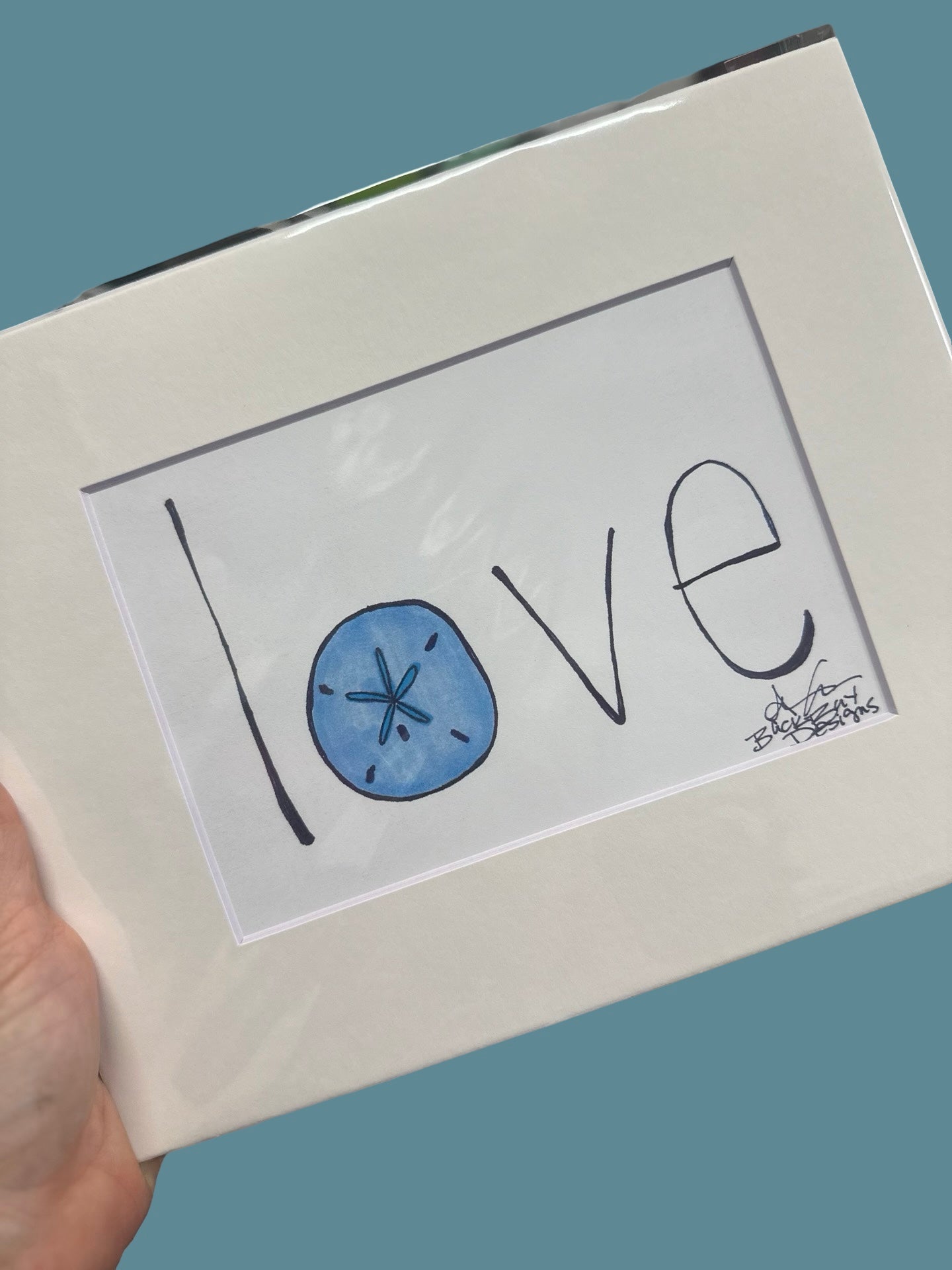 Framed artwork with 'love' text and a blue sand dollar design on a gray background