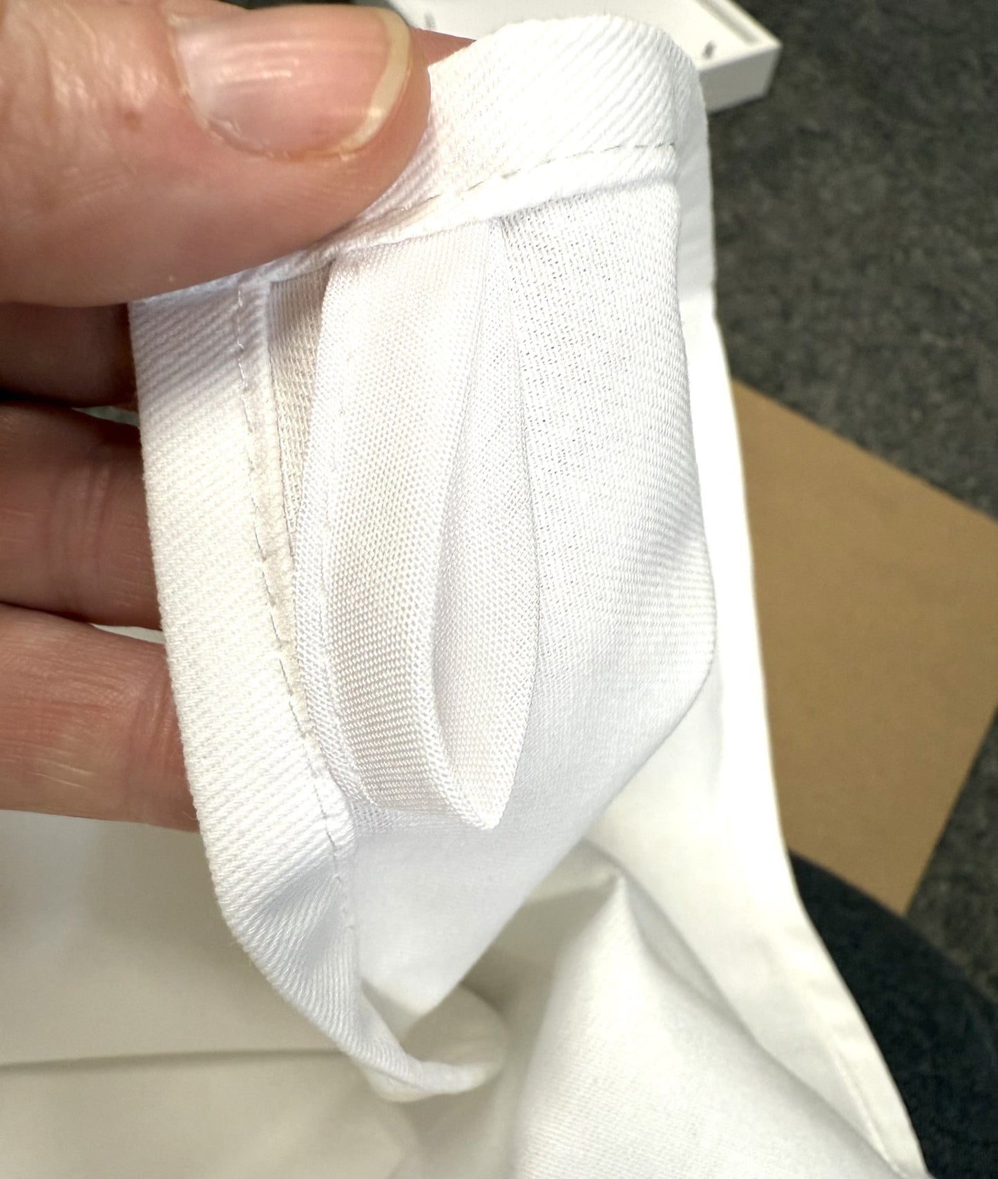 Close-up of a white fabric item held by a hand with a blurred background