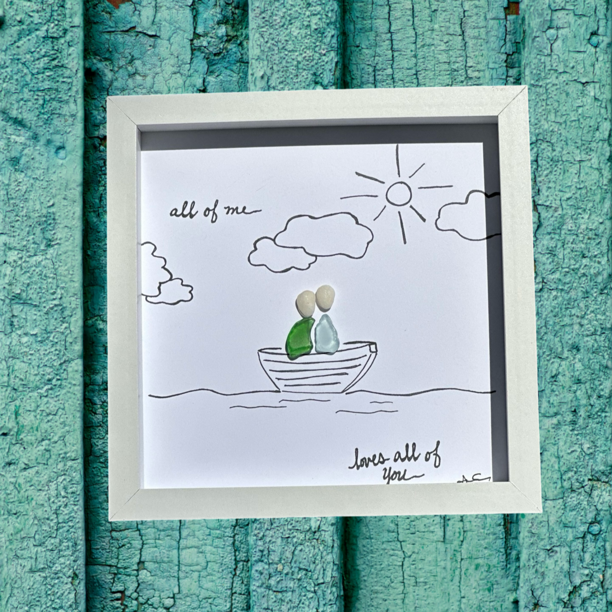 A framed seaglass art piece with heartwarming calligraphy and a drawing of two people in a boat, all of me loves all of you sea glass art 