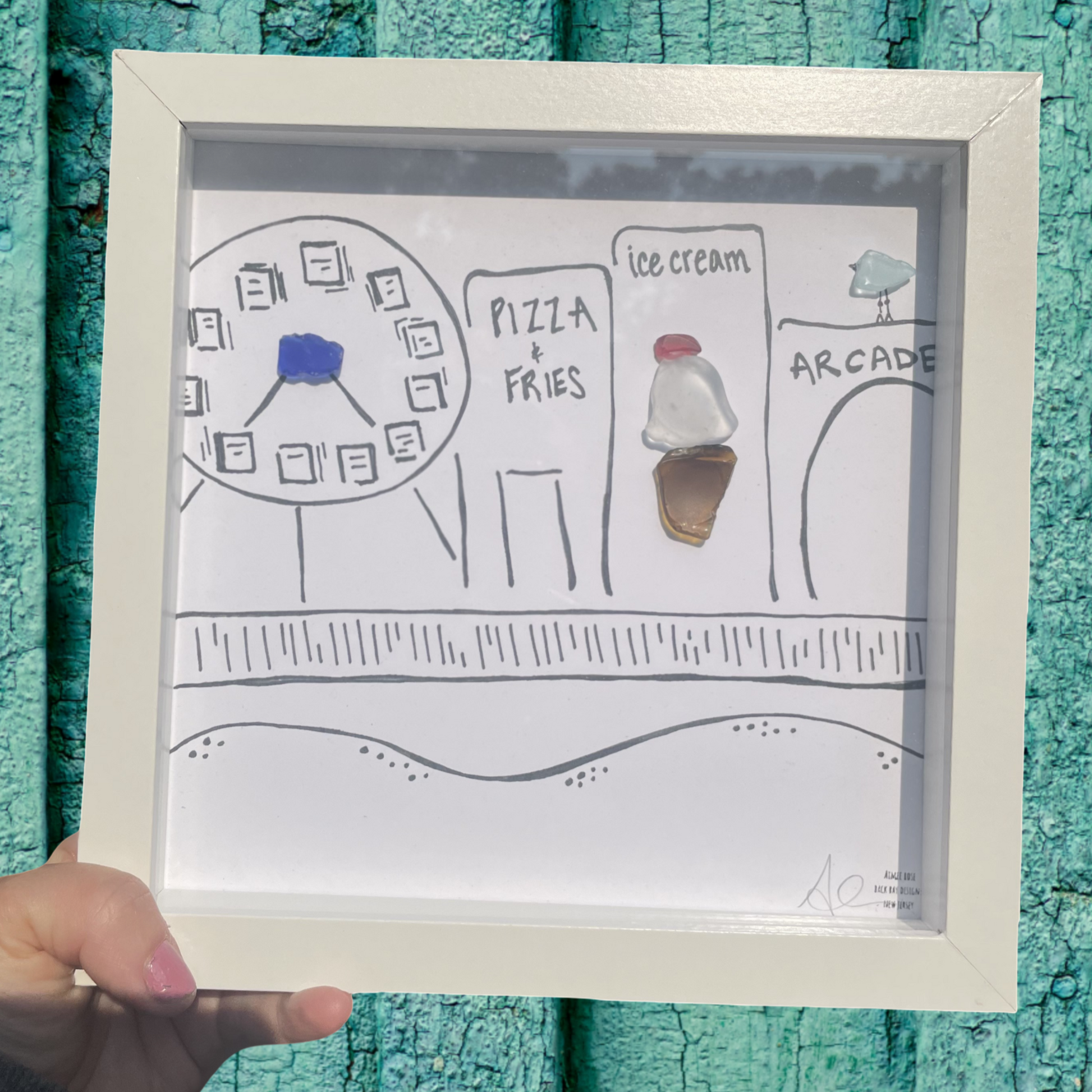Framed drawing of a child's layout of a day with pizza, fries, ice cream, and arcade boardwalk sea glass art 