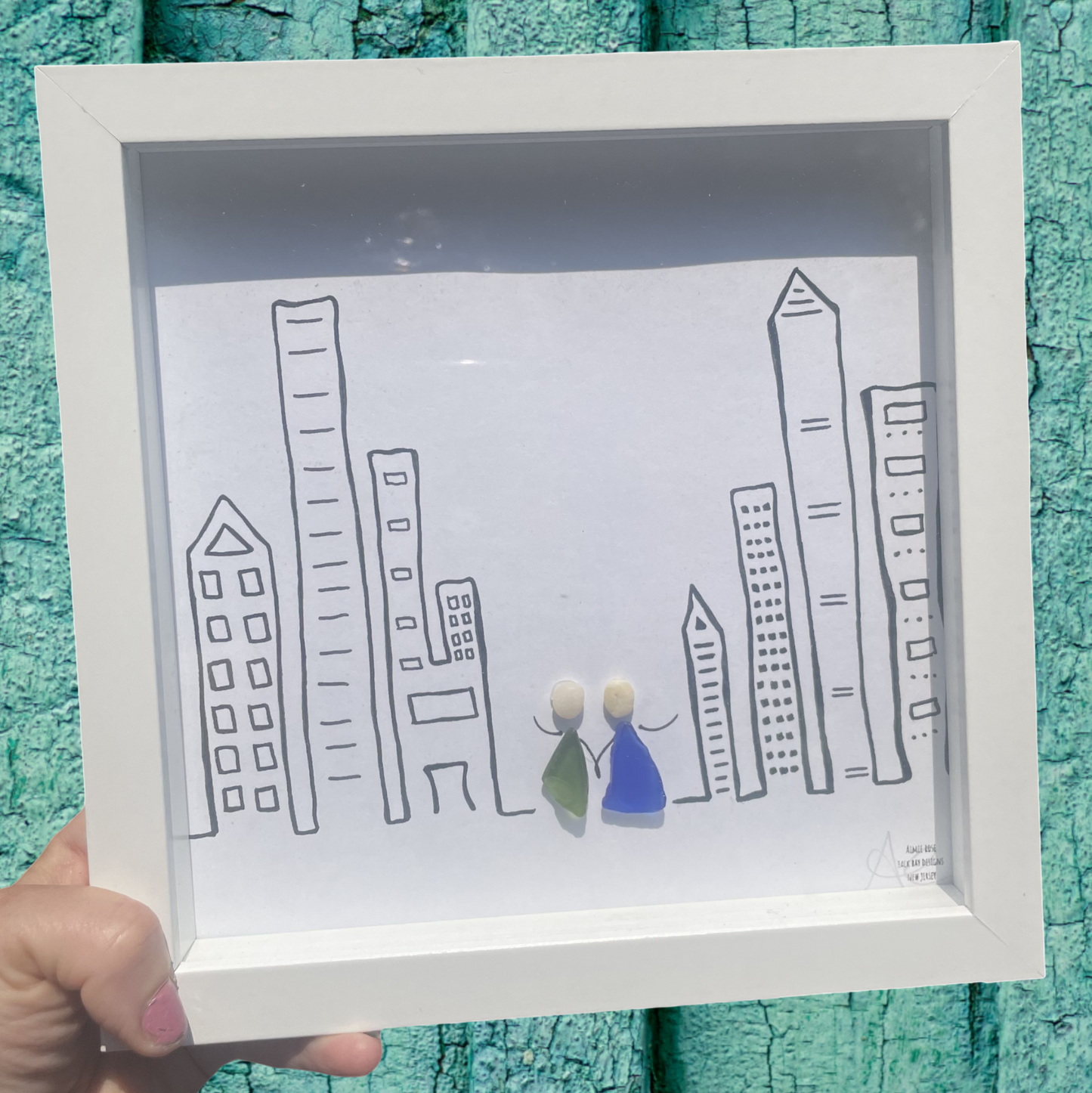 Framed drawing of a cityscape with two people sea glass art 