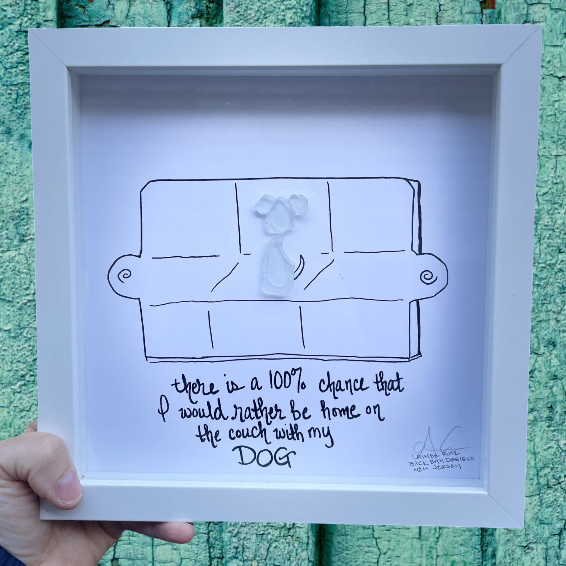Framed artwork with a drawing of a person on a couch and text, 100% chance id rather be on the coach with my dog sea glass art 