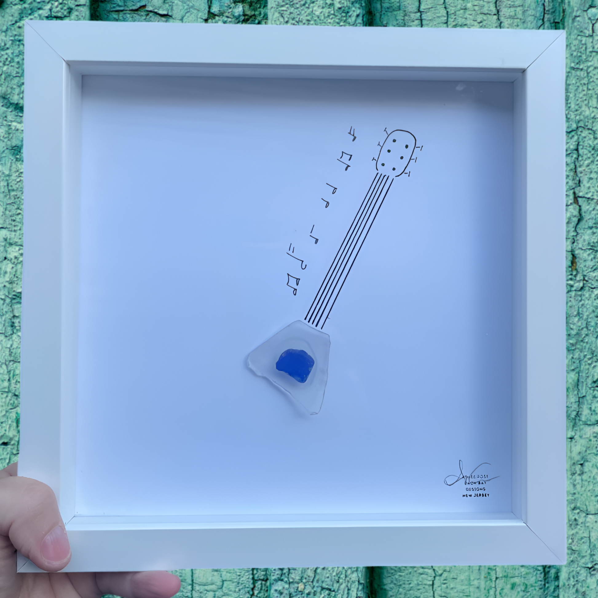 Framed artwork of a sea glass art guitar and music notes 