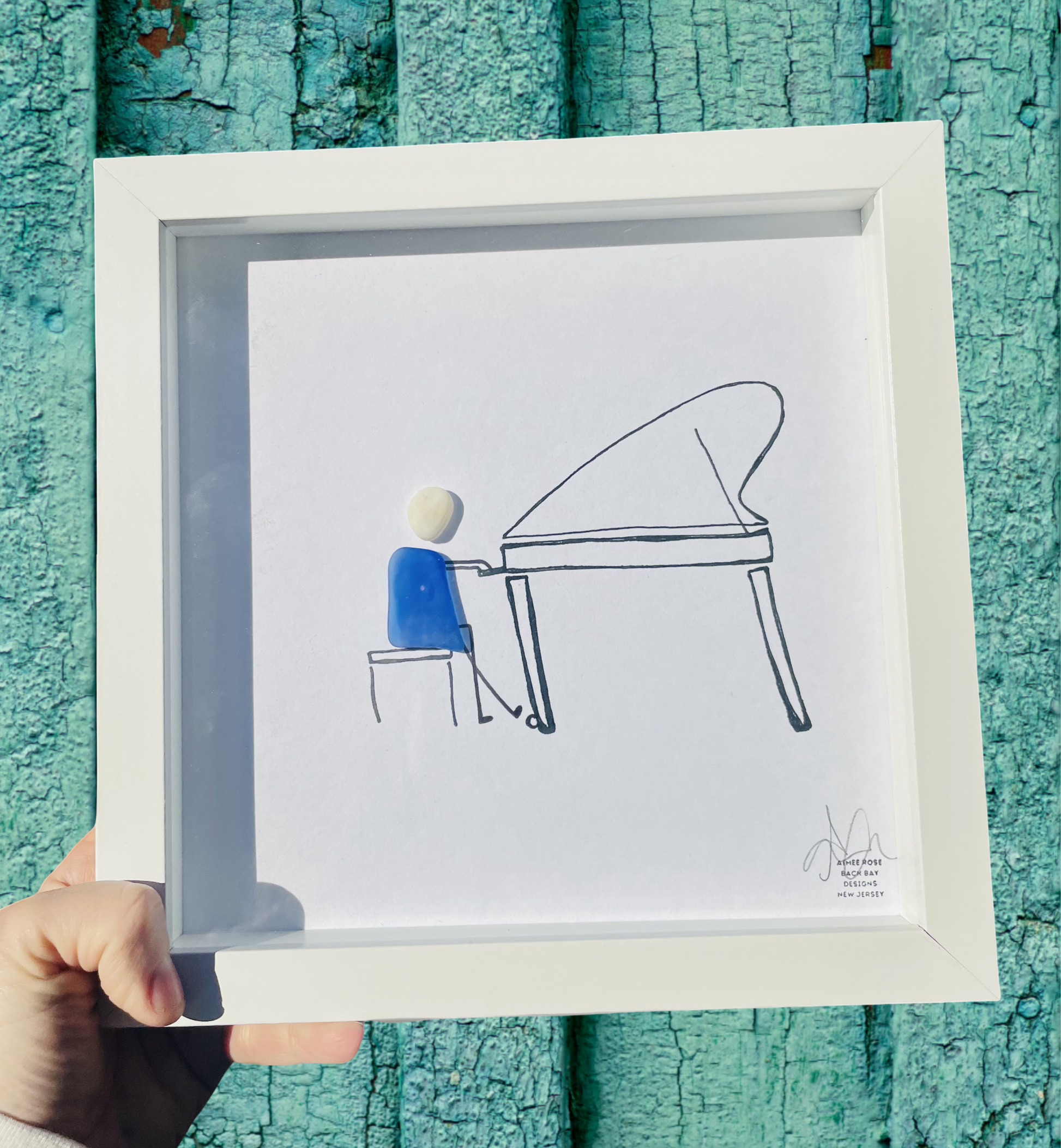 Framed artwork of a person playing a piano against a teal textured background