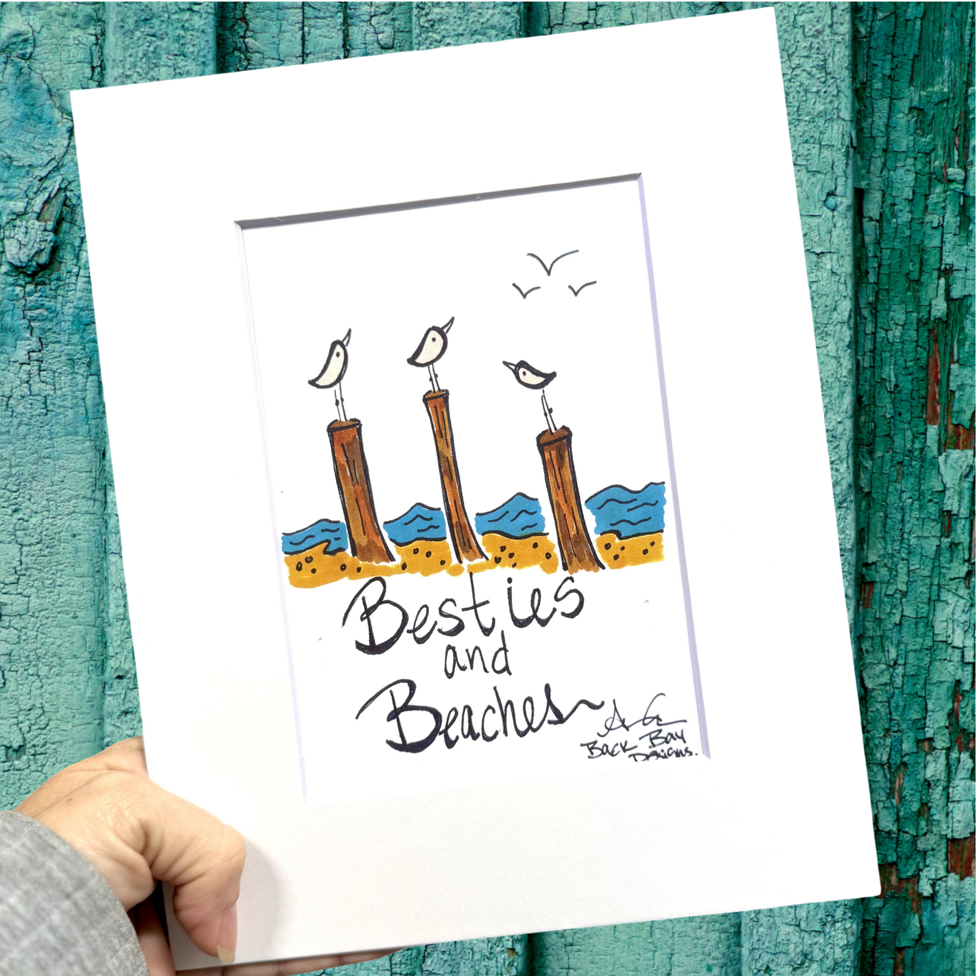 print artwork with beach-themed design featuring pilings beach and birds, held against a textured teal background.