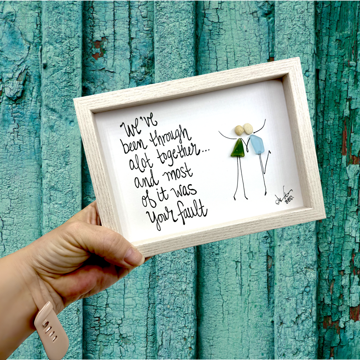 Quote: "We've been through alot together... and most of it was your fault" Image: Two sea glass friends with pebble heads and hand-drawn arms raised, holding hands and one kicking up a leg